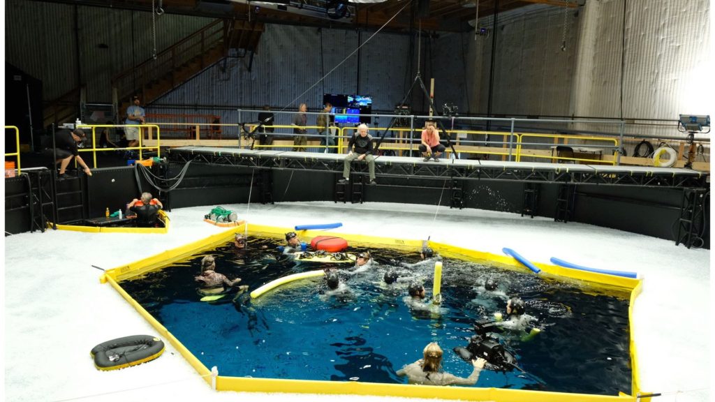 From the set of the sequels: Cameron directing the actors before they dive underwater. Fun fact: That layer of white on the water's surface is comprised of floating balls that prevent lights from interfering with filming underwater. Picture: Avatar Twitter