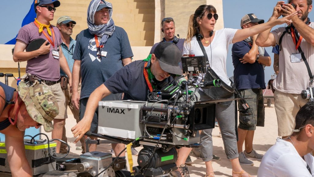Cinematographer Matthew Jensen ASC at the IMAX film camera, with Patty director and crew, during production on Warner Bros.’ Wonder Woman 1984. Photo by Clay Enos. Copyright © 2018 Warner Bros. Entertainment Inc.