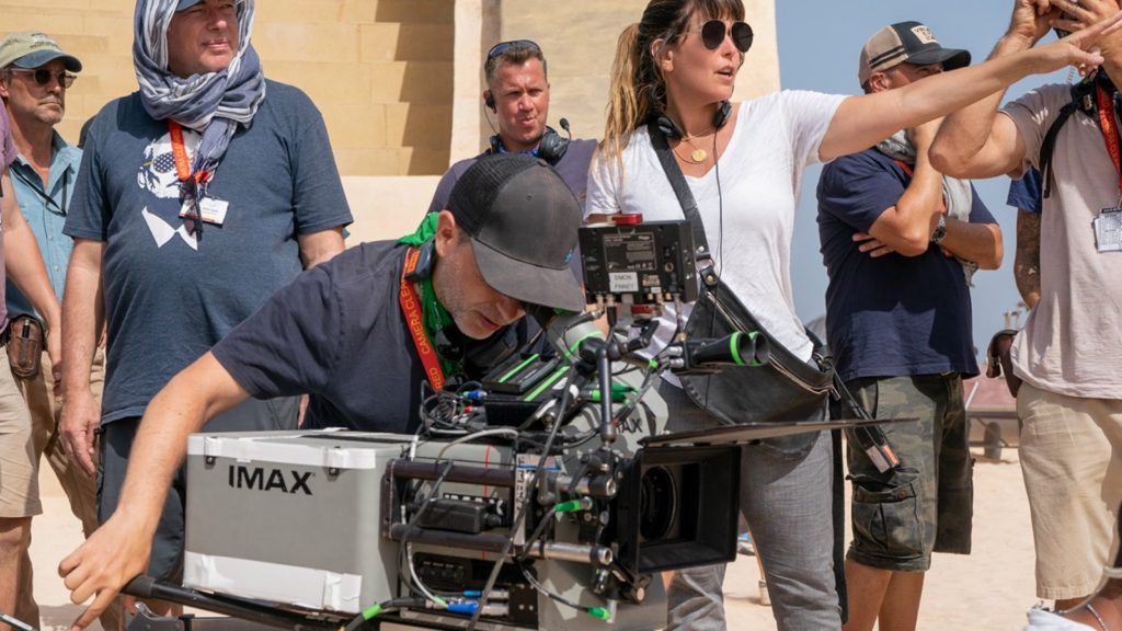 Cinematographer Matthew Jensen ASC at the IMAX film camera, with Patty director and crew, during production on Warner Bros.’ Wonder Woman 1984. Photo by Clay Enos. Copyright © 2018 Warner Bros. Entertainment Inc.